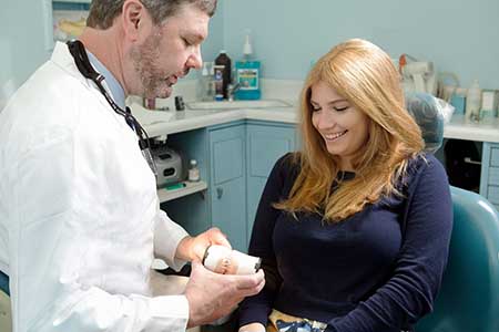 The image shows a dental hygienist assisting a patient during a dental appointment.