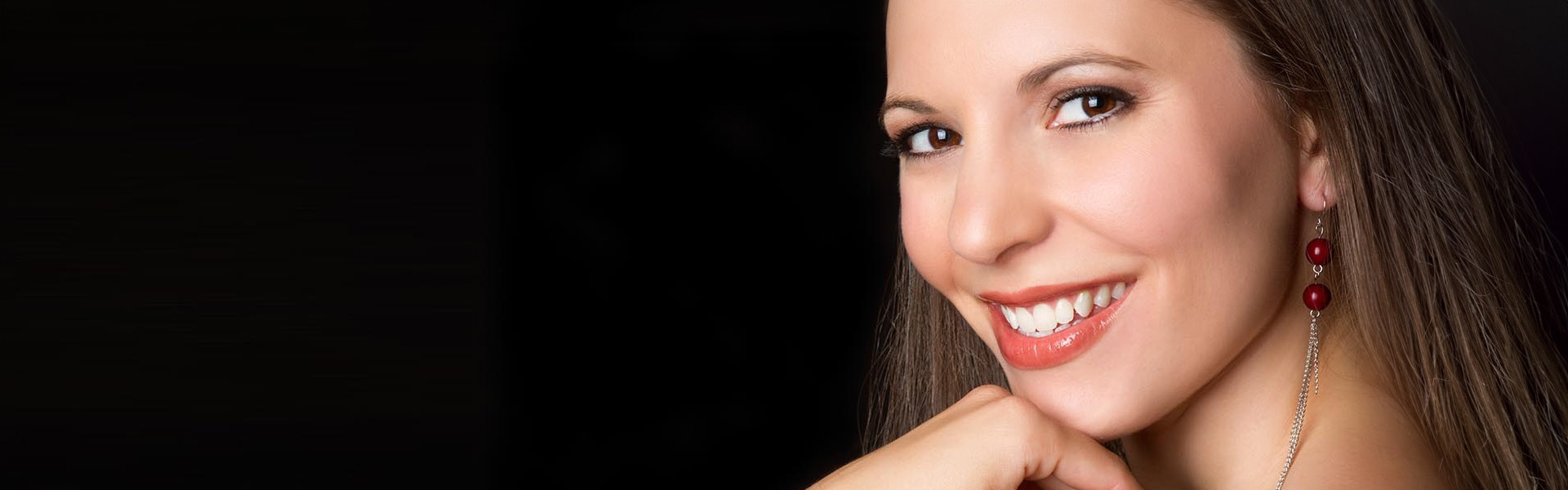 The image features a woman with a radiant smile, posing against a dark background.