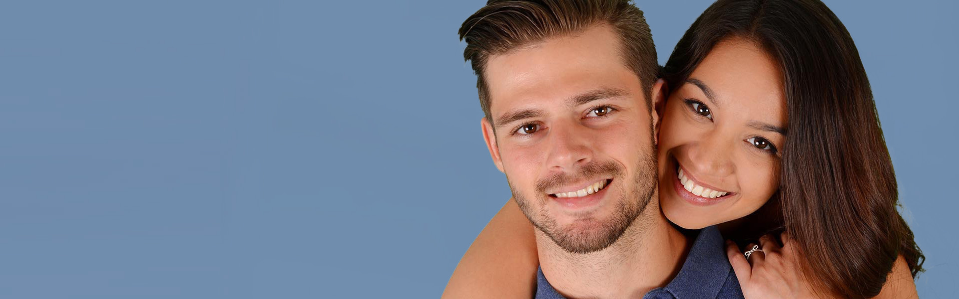 A couple posing together with a blue background.