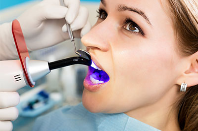 A woman receiving dental treatment with a dentist using a device to clean her teeth.