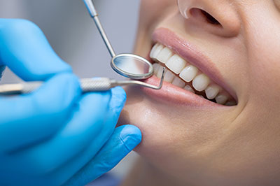 The image shows a person receiving dental care with a smile, while a dental professional works on their teeth using dental instruments, with the focus on oral hygiene and dental treatment.