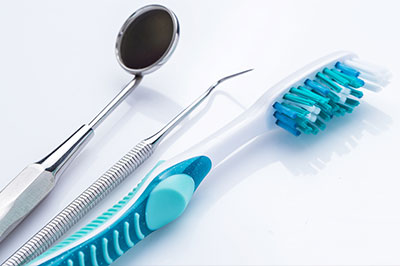 The image shows a collection of dental tools, including a toothbrush with blue bristles, on a white background.