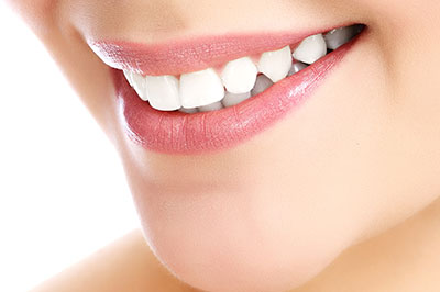 The image displays a close-up view of a person s face with a focus on their teeth and lips, showcasing a smile with white teeth and pink lipstick.