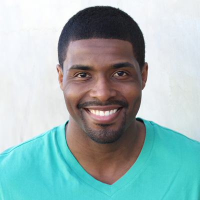 A man and woman are sitting closely together, smiling at the camera.