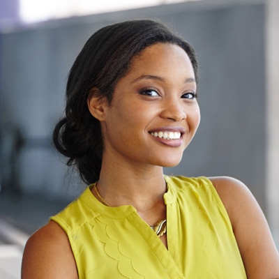 A young woman with a radiant smile poses against a modern backdrop.