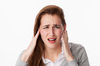 A woman with her hand on her head, appearing to be in distress or pain.