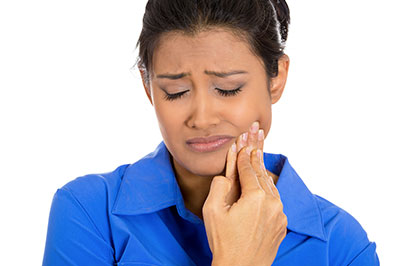 A woman with her eyes closed, holding her nose with her hand, looking distressed or upset, against a white background.