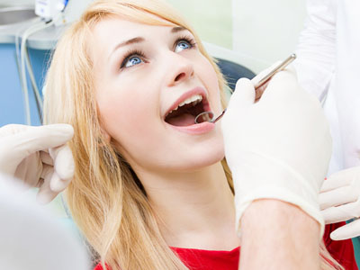 A woman receiving dental care, with a dentist performing a procedure while she sits in a dental chair.